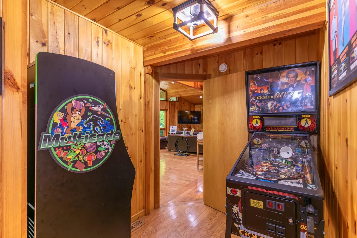A close-up of the Multicade arcade machine and a Goldeneye pinball machine set against wood paneling. The setup evokes a sense of nostalgia and excitement, inviting players to dive into classic games.
